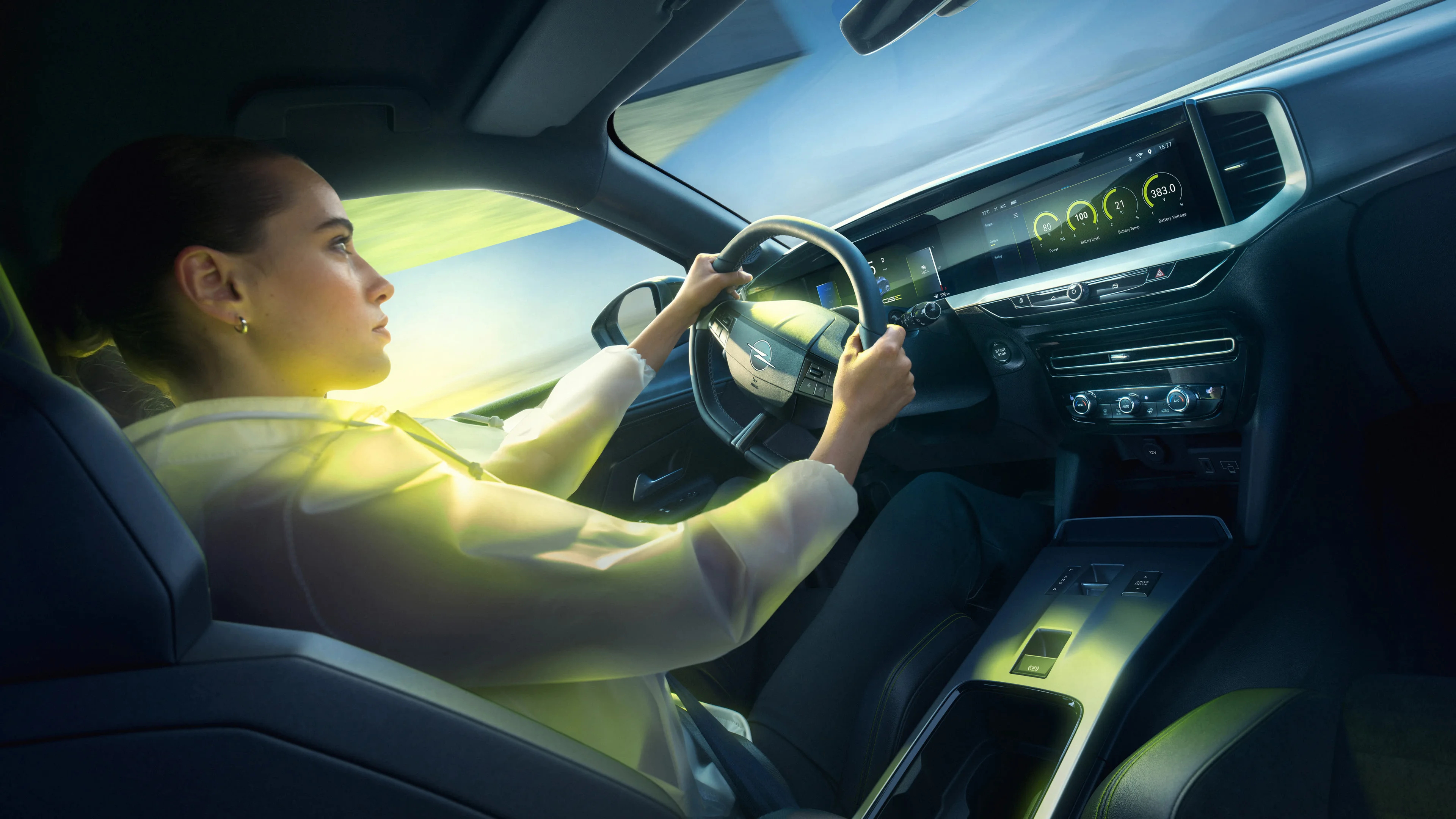 A woman driving an Opel with both hands on the GSE steering wheel, seen from behind and to the side, sunlight falling across the cabin and green countryside blurring past the windows.