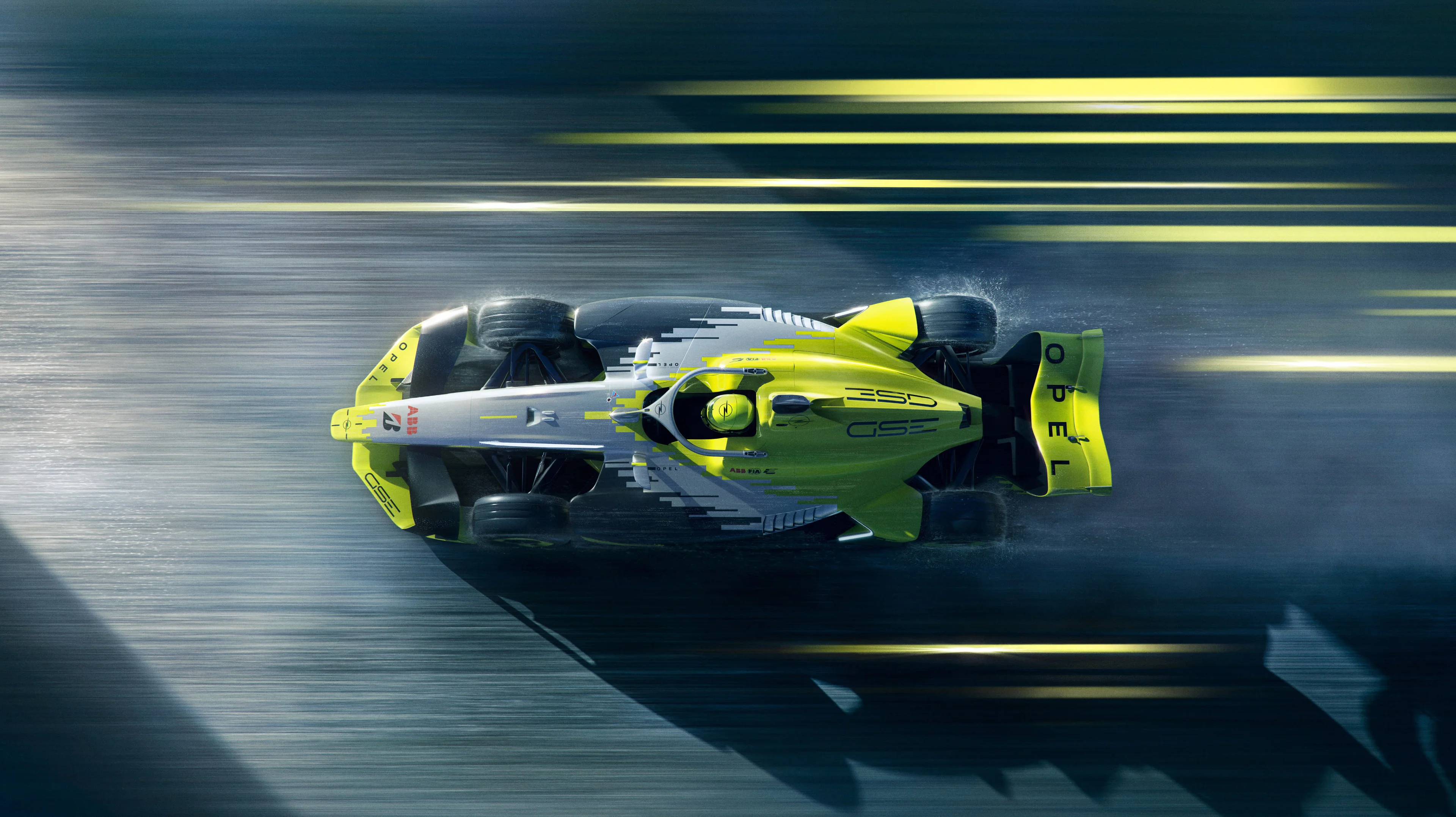 Top-down view of the yellow, silver and black Opel GSE Formula E car racing left on a wet track, with "GSE" on the engine cover and "OPEL" on the rear wing.